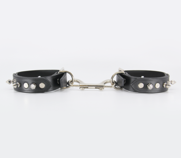 Side view of leather wrist cuffs with 3 short dog spikes with 4 silver rivets on each cuff, connected with double ended snap.