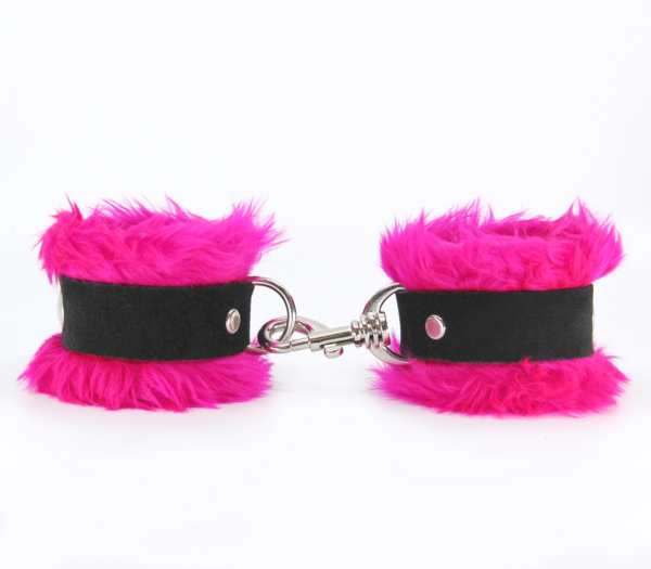 Side view of pink fluffy wrist cuffs with black centre strap and silver snap.