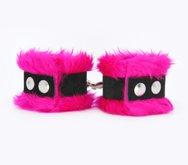 Back view of pink fluffy wrist cuffs with black centre strap and silver snap buttons.