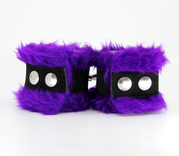Back view of purple fluffy wrist cuffs with black centre strap and silver snap buttons.
