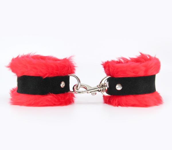 Side view of red fluffy wrist cuffs with black centre strap and silver snap.