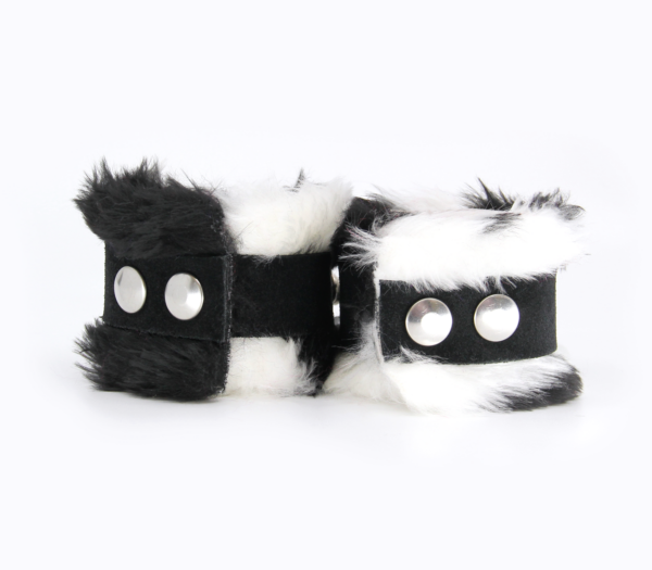 Back view of black and white fluffy wrist cuffs with black centre strap and silver snap buttons.